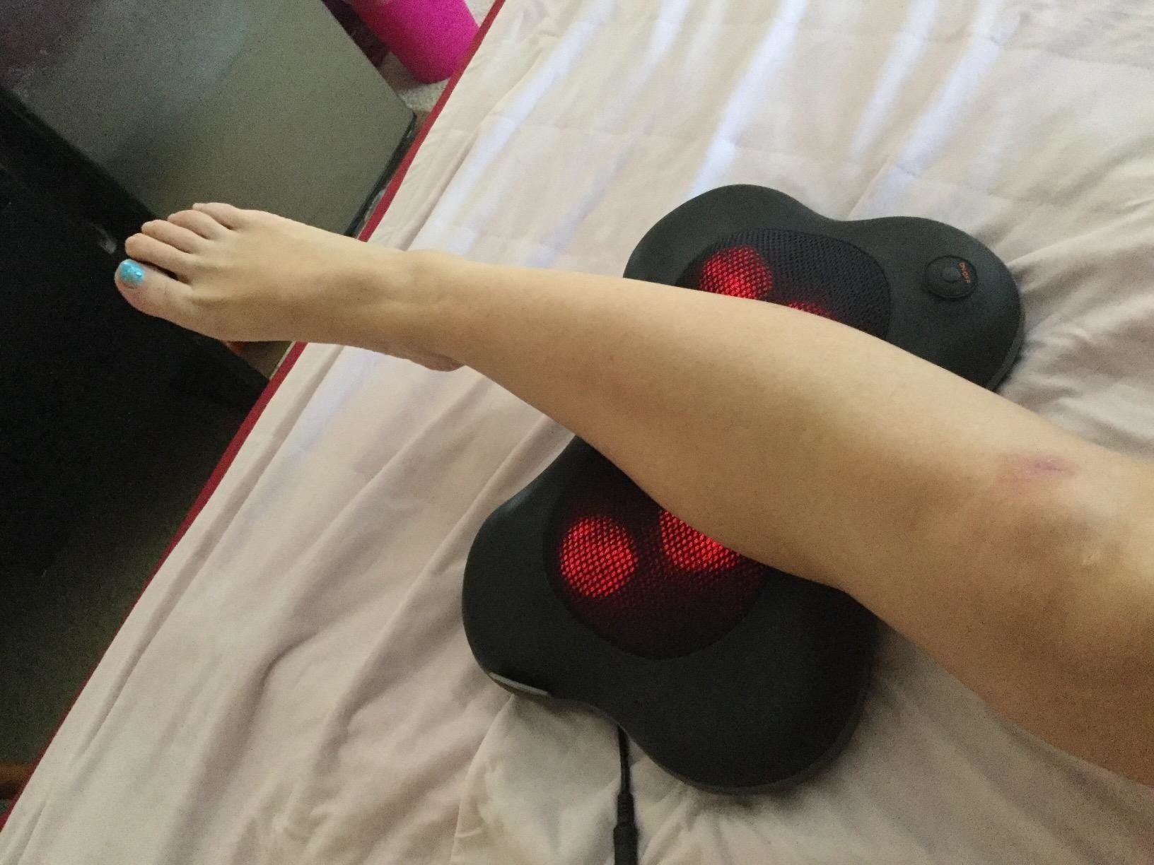 A reviewer using the massager on their calf muscles
